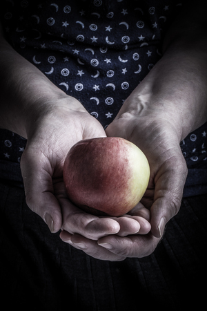 Fresh apple in the hands of an elderly woman. Toned.の写真素材