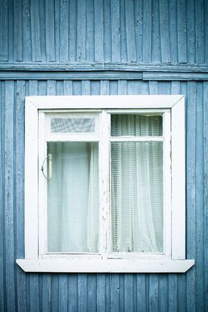 Window on the old wooden houses painted wall. Selective focus. Toned.