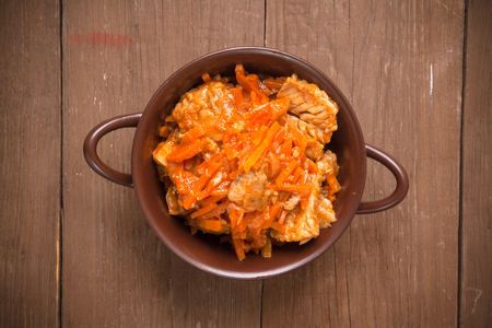 Fish marinated with carrots in a brown ceramic bowl on old wooden table. Toned.の写真素材