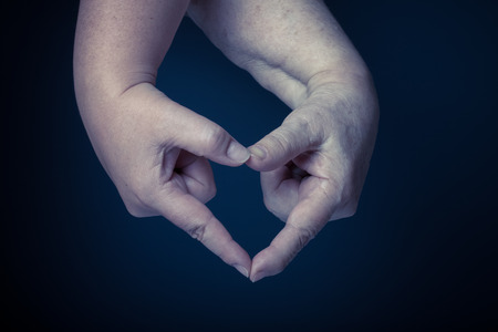 Hands of elderly and young women on black background. Toned.の写真素材