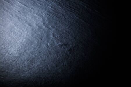 Black textured wall with varying light conditions. Background. Toned.の写真素材