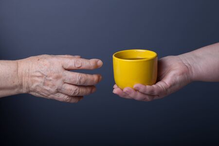 Hands of elderly and young women on black background.