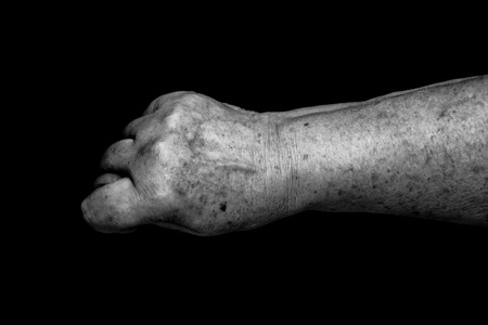 Hands of elderly woman on black background. Toned.の写真素材