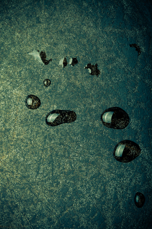 Drops of water on black metal background. The surface of the pan to the oven. Toned.の写真素材