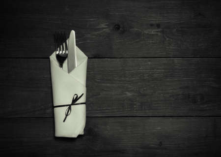 Fork and knife in napkin on wooden background. Toned.の写真素材
