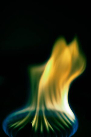 Gas burns on the burner on the stove in the dark. Selective focus. Toned.