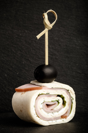 Small rolls with ham, cheese and pita on skewer on a black slate plate. Selective focus. Toned.の写真素材
