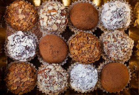 Set of different kinds of homemade chocolate truffles in a golden box.