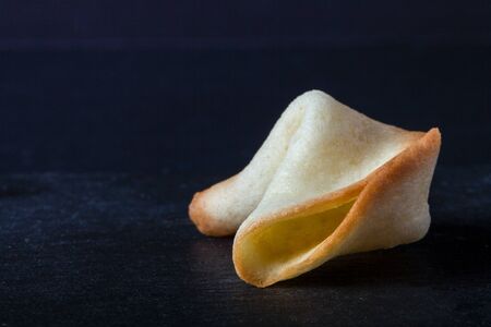 Fortune Cookies with blank paper on a black background. Toned.