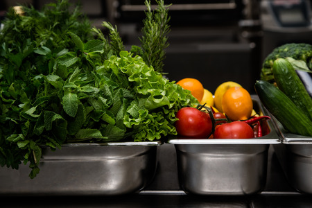 Fresh greens in metal bowl on professional kitchen. Selective focus. Shallow depth of field.の写真素材