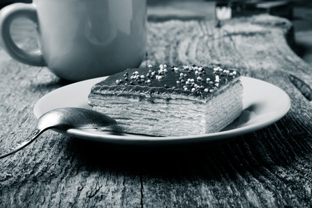 Tasty chocolate waffle cake and yellow cup of coffee on old wooden table. Selective focus. Toned.の写真素材
