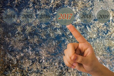 Hand of a young girl points to a figures 2017 opposite beautiful nature pattern on frosted glass for...