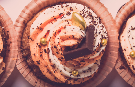 Vanilla cupcakes with orange and white creamcheese and chocolate decor. Toned.の写真素材