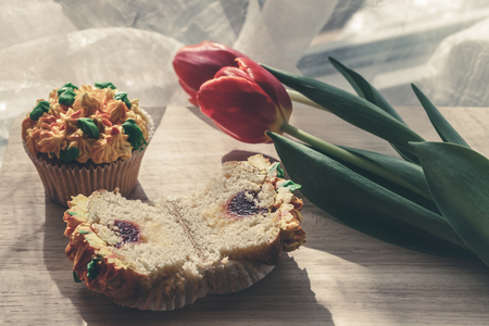 Yummy cupcake and red tulips on light background. Selective focus. Toned.の写真素材