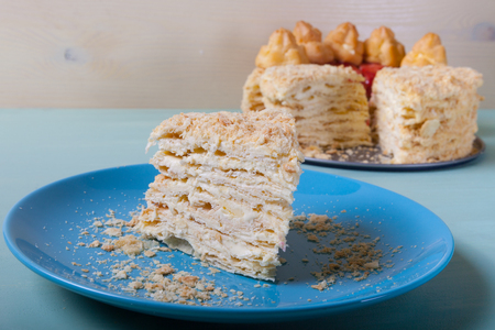 Homemade puff cake with brewed creamy cakes as decor on a light background. Shallow depth of field....