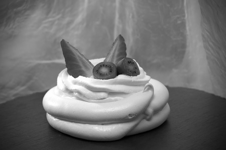 Homemade mini Pavlova meringue cake with fresh strawberries and kiwi on a light background. Toned.の写真素材