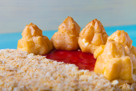 Homemade puff cake with brewed creamy cakes as decor on a light background. Shallow depth of field....