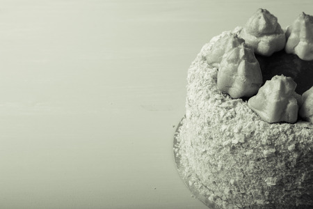 Homemade puff cake with brewed creamy cakes as decor on a light background. Toned.