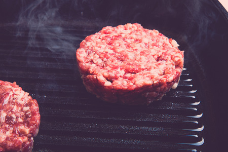 Fresh meat cutlets in a frying pan grill. Selective focus. Shallow depth of field. Toned.の写真素材