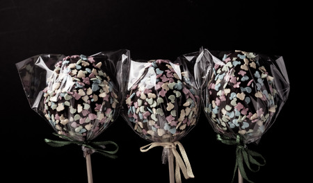 Homemade tiny cakes - cake pops in egg shape on a dark background. Easter theme. Toned.