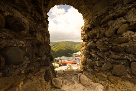 Beautiful autumn mountain landscape in Kakheti view through the loophole in an ancient stone wall. Georgia. Toned.の写真素材