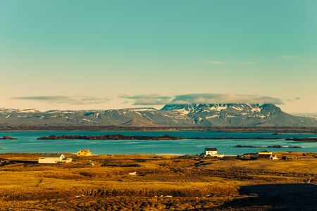 Small houses on the coast of lake on stony rocky deserted landscape of Iceland. Toned.の写真素材