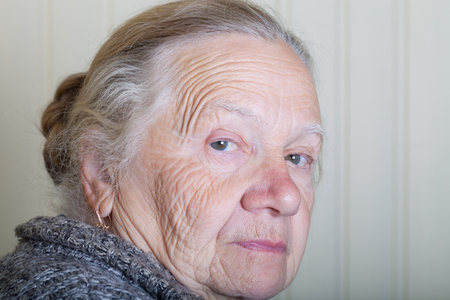 Portrait of an elderly woman on a light background. Thoughtful profile.の写真素材