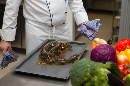 Fresh prepared fish sterlet in a metal oven of restaurant kitchen. Selective focus. Shallow depth of field.の写真素材