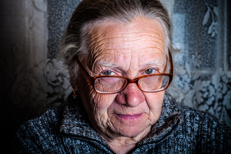 Elderly woman with glasses in rustic interior. Toned.の写真素材