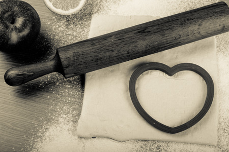 Set for home baking on a light wooden table with flour. Rolling pin, baking form, dough, half of lemon, apple. Toned.の写真素材
