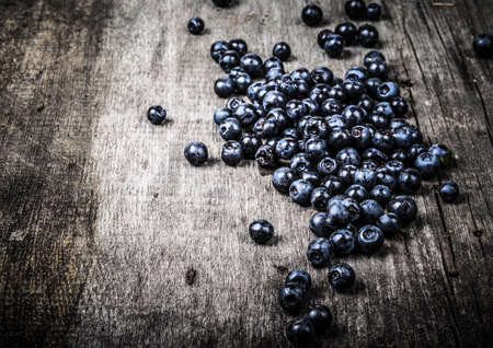 Blueberries collected manually scattered on the old gray wooden board. Toned.の写真素材