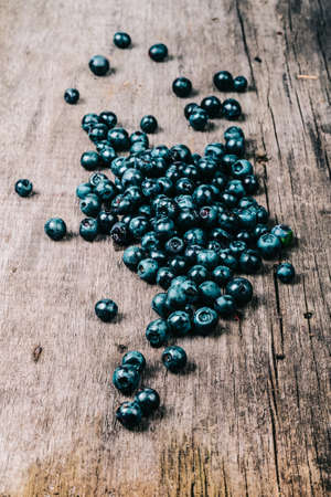 Blueberries collected manually scattered on the old gray wooden board. Toned.の写真素材