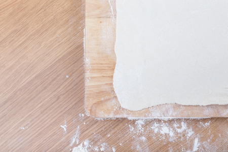 Puff dough, wooden cutting board on a light table with flour.