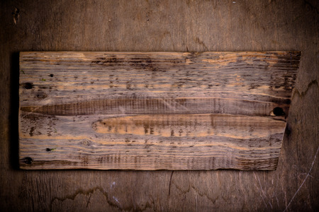 Handmade burned cutting board on a wooden rustic texture for background. Rough weathered wooden board. Toned.の写真素材