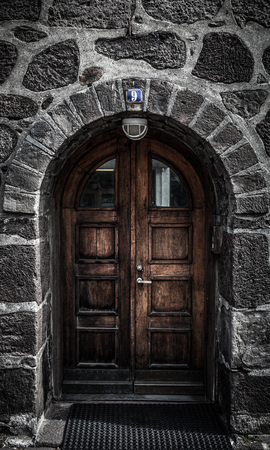 Wooden door on a wall built of natural stone. Toned.の写真素材