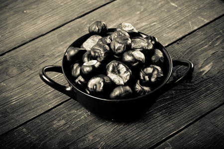 Chestnuts in a clay bowl on the old wooden background. Toned.の写真素材