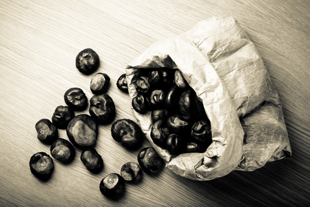 Chestnuts in a paper bag on a light wooden table. Toned.の写真素材
