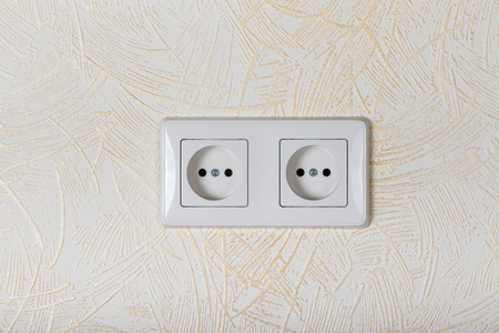 Light wallpaper on a wall with electrical outlet for background. Close Up detail.