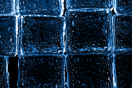 Wet ice cubes on black background. Selective focus. Toned.