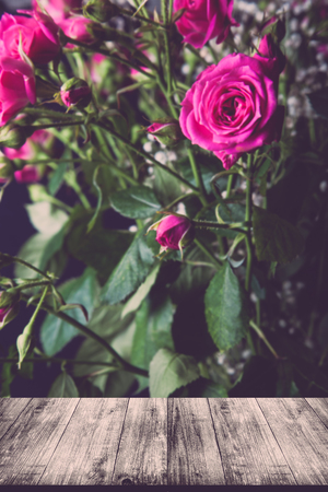 View from wooden table on wonderful bouquet of bush roses and gypsophila on a dark background. Selective focus. Shallow depth of field. Toned.の写真素材