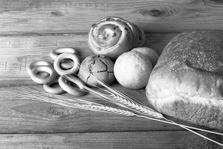 Different types of fresh bread and wheat spikes on old wooden table. Toned.の写真素材