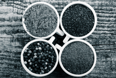 White ceramic cups with different kinds of spices on old wooden board. Selective focus. Toned.の写真素材