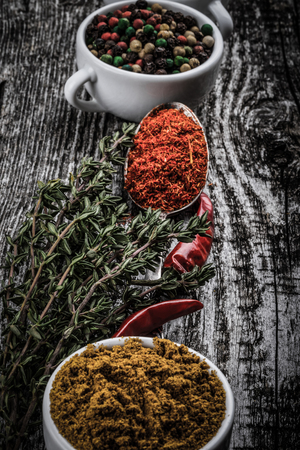 White ceramic cups with different kinds of spices on old wooden board. Selective focus. Toned.の写真素材