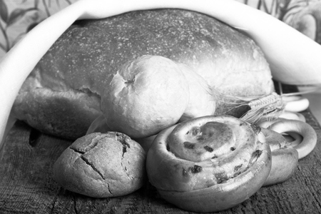 Different types of fresh bread and wheat spikes on old wooden table. Shallow depth of field. Selective focus. Toned.の写真素材