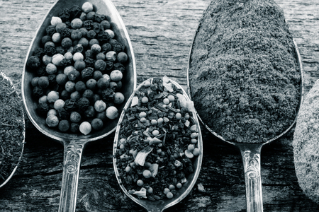 Antic metal spoons with different kinds of spices on old wooden board. Selective focus. Toned.の写真素材