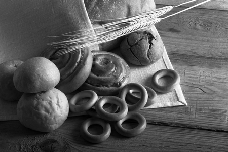 Different types of fresh bread and wheat spikes on old wooden table. Toned.の写真素材
