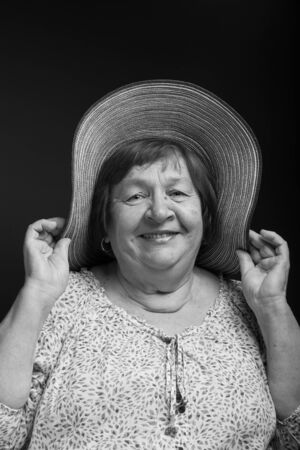 Studio portrait of elderly woman with hat. Smile. Toned.の写真素材