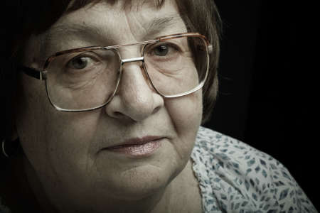 Studio portrait of elderly woman with glasses. Calmness. Toned.