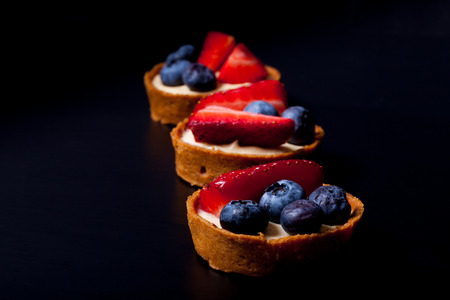 Berry tartlets with blueberries, strawberries and butter cream. Shallow depth of field. Selective focus.の写真素材