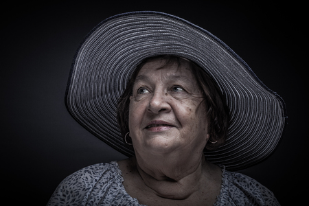 Studio portrait of elderly woman with hat. Smile. Toned.の写真素材